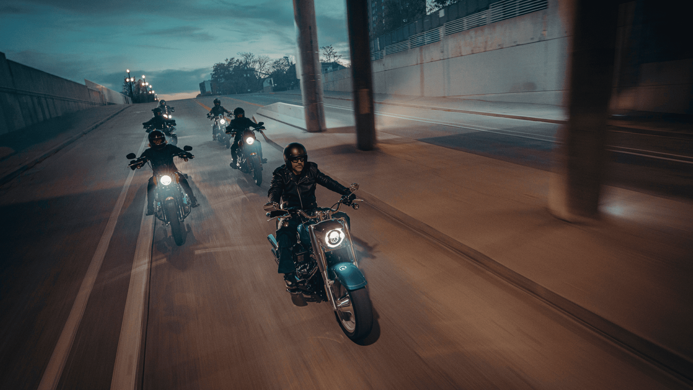 A group of riders on Harley-Davidson motorcycles cruising down a street near Orlando, FL, showcasing the MY2025 lineup. Available at Space Coast Harley-Davidson® 