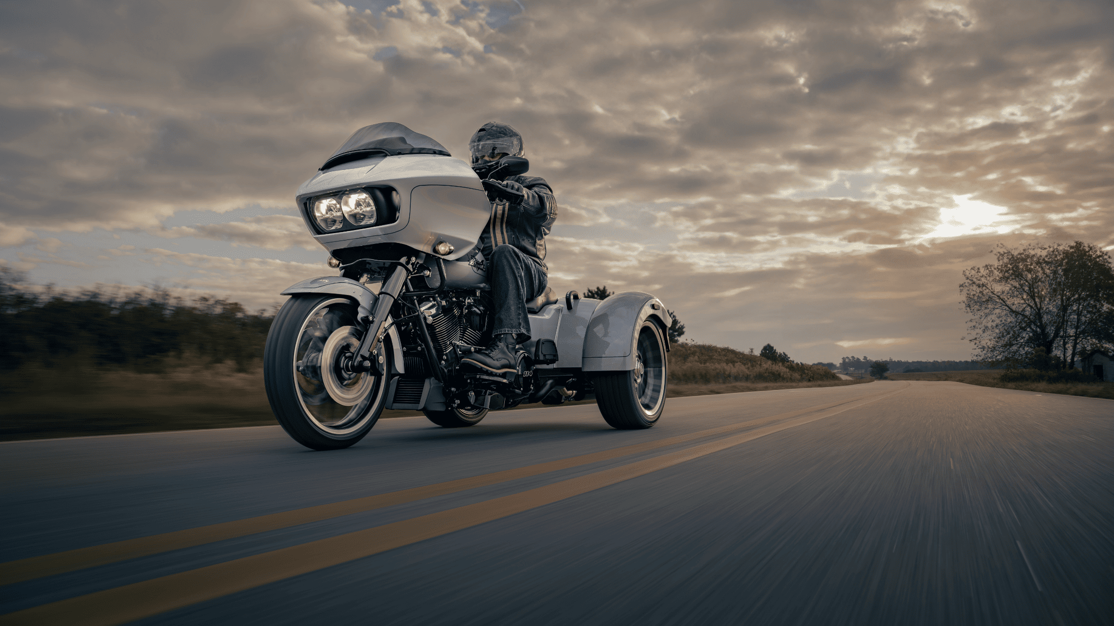 Rider cruising a 2025 Harley-Davidson Road Glide 3 trike on open road near Sanford, FL at sunset