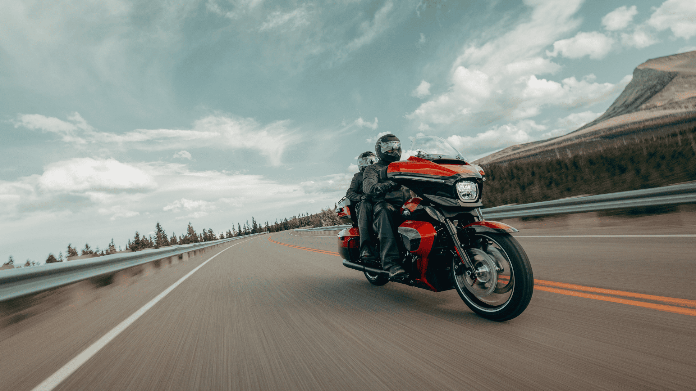 A rider on a red 2025 Harley-Davidson® Street Glide® Ultra cruising down a highway in Sanford, FL.